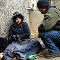 Man talking to homeless woman with dog