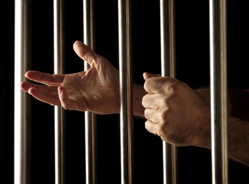 hands of a prisoner behind bars