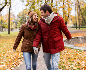 love, relationships, season and people concept - happy young couple walking in autumn park and talking