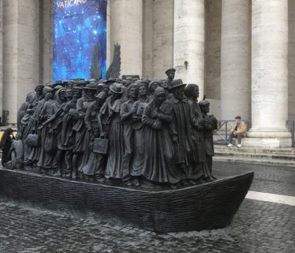 Un code QR devant une statue place Saint Pierre rappelle la politique du pape pour les migrants