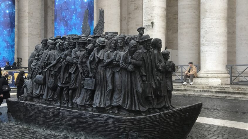Un code QR devant une statue place Saint Pierre rappelle la politique du pape pour les migrants